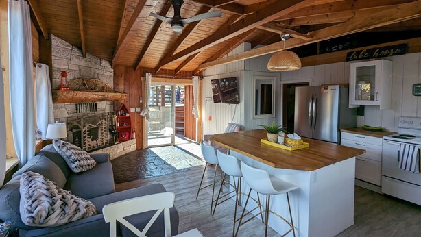 Een gezellig houten interieur met een stenen openhaard, houten balken in het plafond, een eethoek met een bar en een keuken met moderne apparatuur.