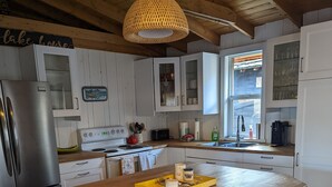Een keuken met een houten keukeneiland, witte kasten, roestvrijstalen apparatuur en een hanglamp.
