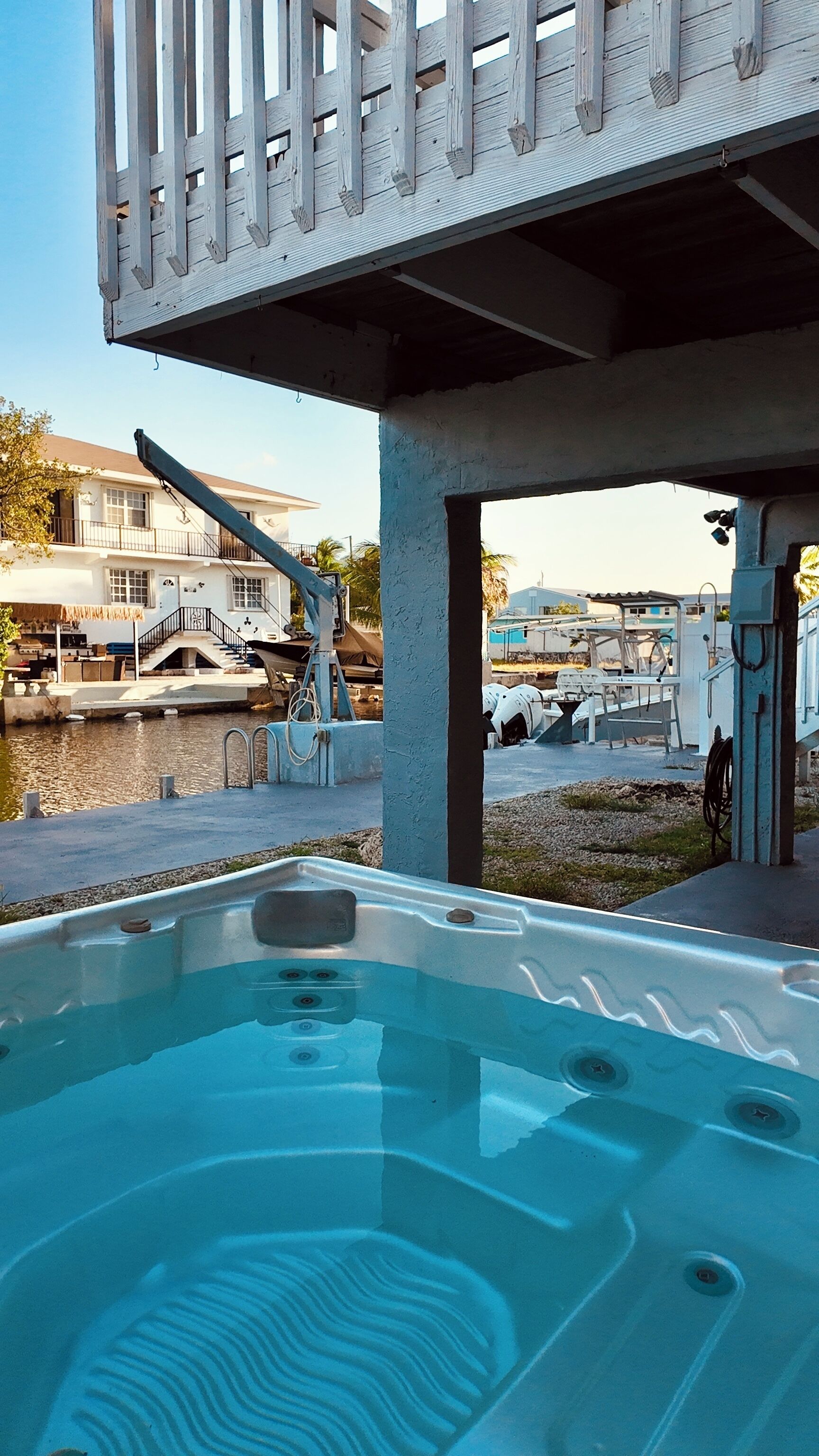 A hot tub under a balcony with a view of a residential area and water body.