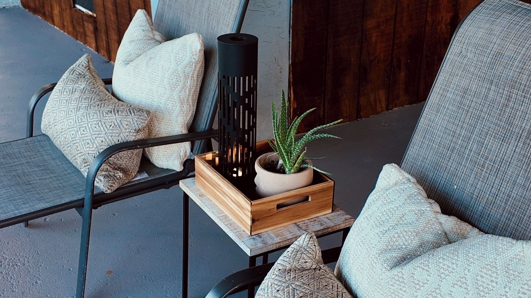 A seating area with a wooden crate containing a potted plant and a black vase.