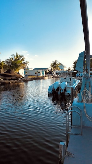 A marina with boats docked, calm water, and a building with a blue roof in the background. - Canal-Front Keys Retreat with Jacuzzi • Sleeps 12 (Big Pine Key)