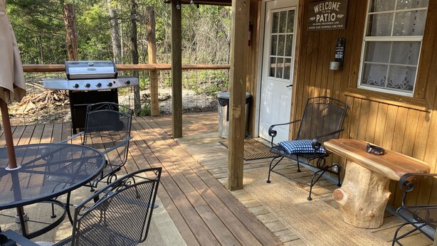 A wooden deck with a grill, metal chairs, and a bench. - Deadwood acres cabin #3 (Eminence)