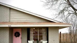 Une maison avec une porte rose, une façade en briques et le numéro « 926 » affiché sur le devant.