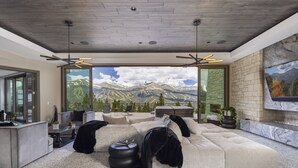Ein modernes Wohnzimmer mit einer großzügigen Eckcouch, einem Kamin und Bergblick durch große Fenster.