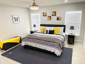 A bedroom with a bed, bedside tables, a lamp, a rug, and wall art.