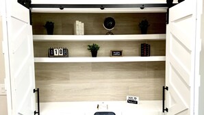 Ein Zimmer mit einer Schiebetür, hinter der sich ein Arbeitsbereich mit Regalen, einem Stuhl und einem Schild mit dem WLAN-Passwort befindet.