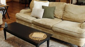 A cozy living room with a sofa, a coffee table, and a kitchen in the background. - Spring thaw-summer is on the horizon!  (Annandale)