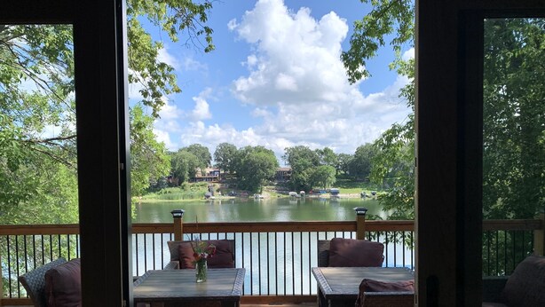 A deck with wicker furniture and a table, overlooking a lake with boats and houses in the background. - Spring thaw-summer is on the horizon!  (Annandale)