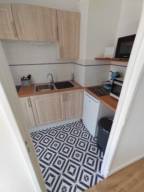 A compact kitchen with a sink, a small refrigerator, and a microwave. - Studio à la Plage (Concarneau)