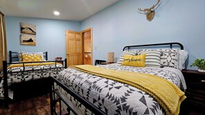 Une chambre avec deux lits, une porte en bois et une décoration murale représentant une tête de cerf.