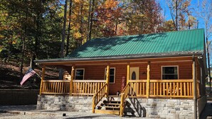 A wooden cabin with a green roof, stone foundation, and a wooden porch with a railing. - Sugar Bear Cabin 5 mins from State Park!  Fishing, w/boat parking, golf & more! (Burkesville)