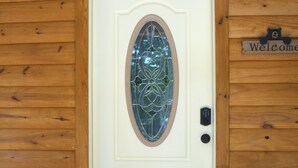A white door with a decorative glass panel, a welcome sign, and a potted plant on a wooden porch. - Sugar Bear Cabin 5 mins from State Park!  Fishing, w/boat parking, golf & more! (Burkesville)