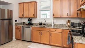 A modern kitchen with wooden cabinets, stainless steel appliances, and granite countertops.