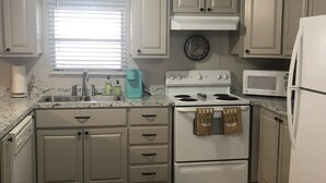 A compact kitchen with white cabinets, a stove, a microwave, and a refrigerator. - Slice of Heaven 3/2 camp on lakefront w/ boathouse (Zwolle)