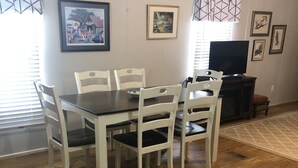 A dining area with a dark wooden table and white chairs, a television, and framed artwork on the walls. - Slice of Heaven 3/2 camp on lakefront w/ boathouse (Zwolle)