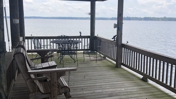 A wooden deck with a covered seating area overlooking a body of water. - Slice of Heaven 3/2 camp on lakefront w/ boathouse (Zwolle)