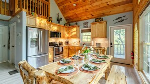 A kitchen with wooden cabinets, a stainless steel refrigerator, and a dining table set for six.