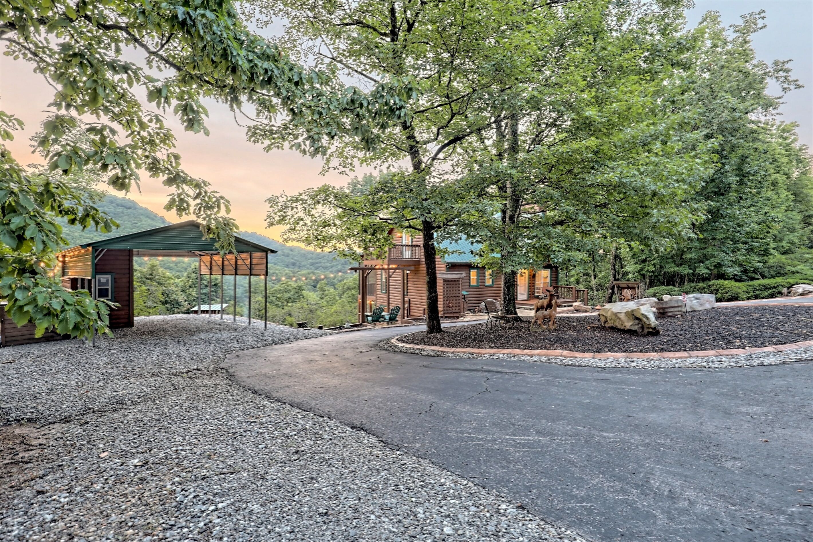 Un chalet rustique doté d’un porche abrité, entouré d’arbres et accessible par une allée de gravier.