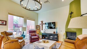 A living room with leather sofas, a coffee table, a fireplace, and a television.