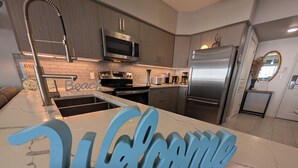 Una cocina moderna con electrodomésticos de acero inoxidable, encimera de mármol y un cartel que dice 'Welcome'.