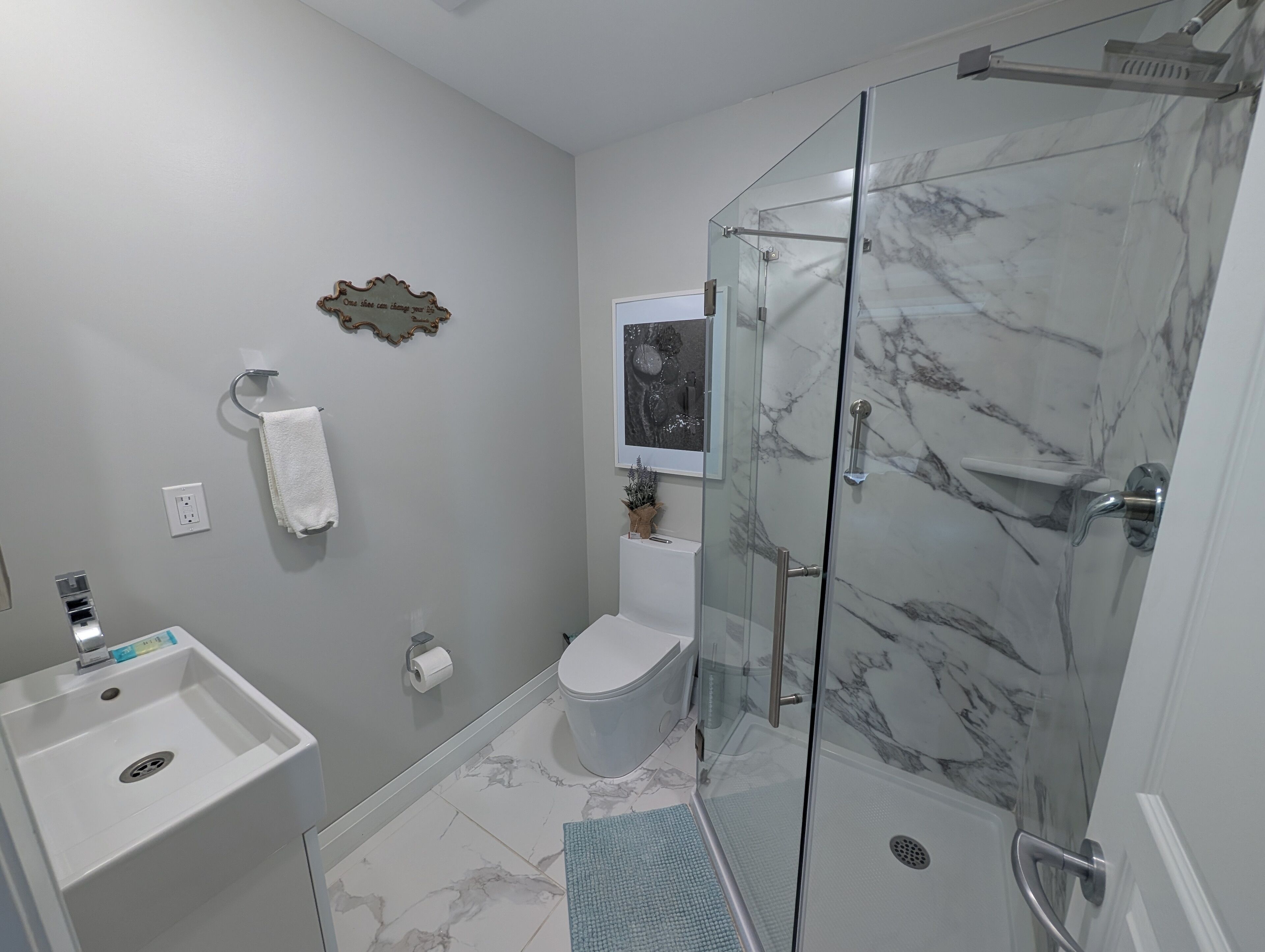 A modern bathroom with a glass shower enclosure, a white sink, and a toilet.