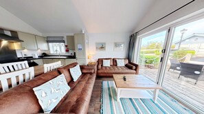Een moderne woonkamer met een zithoek, een salontafel en uitzicht op de omgeving.
