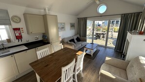 A compact living space with a dining area, kitchenette, and a balcony with a view. - Stunning Beach House - Sleeping 4 in 2 Bedrooms - Pool and Beach Access Included. (Filey)