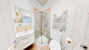 A modern bathroom with a glass-enclosed shower, a sink with a mirror, and a toilet. - Stunning Beach House - Sleeping 4 in 2 Bedrooms - Pool and Beach Access Included. (Filey)