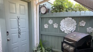 Una puerta con un cartel de bienvenida, un reloj, una cerca decorativa y una parrilla.