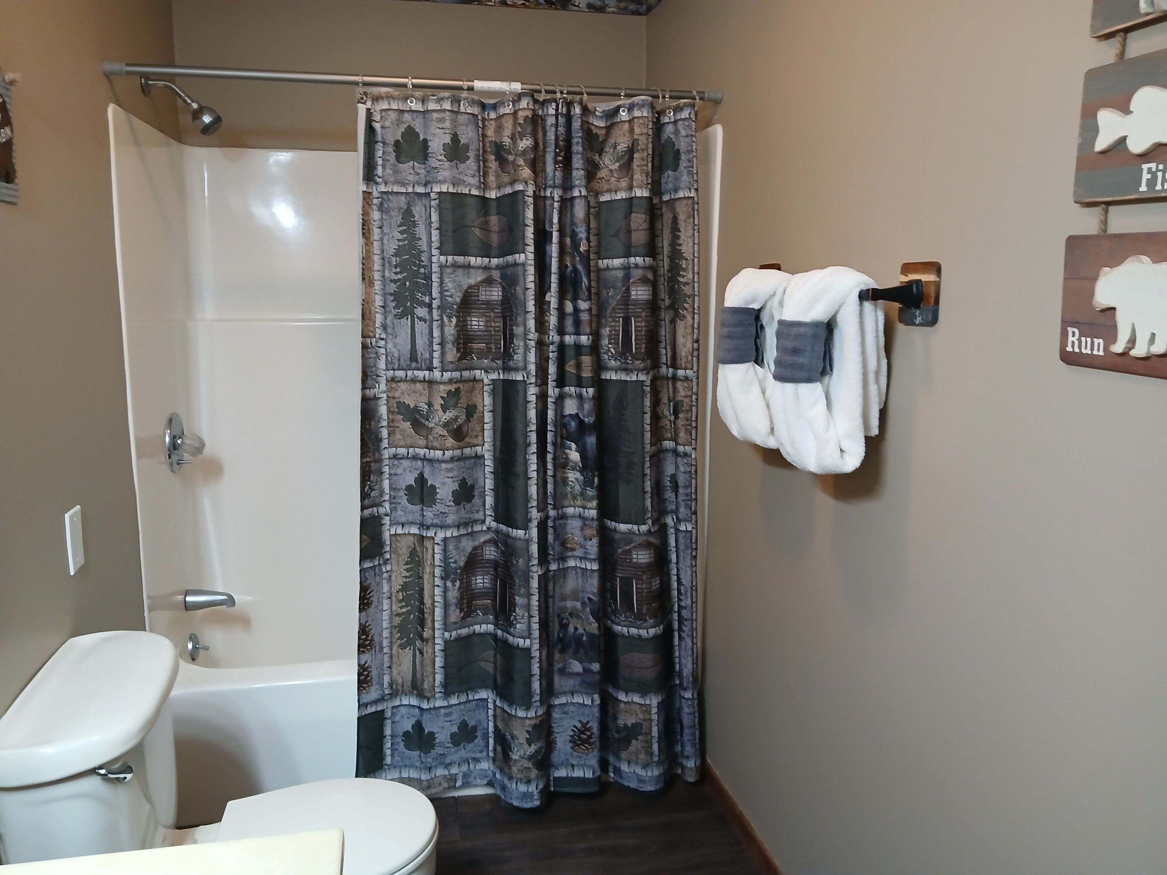 A bathroom with a shower, toilet, and a towel rack with towels.