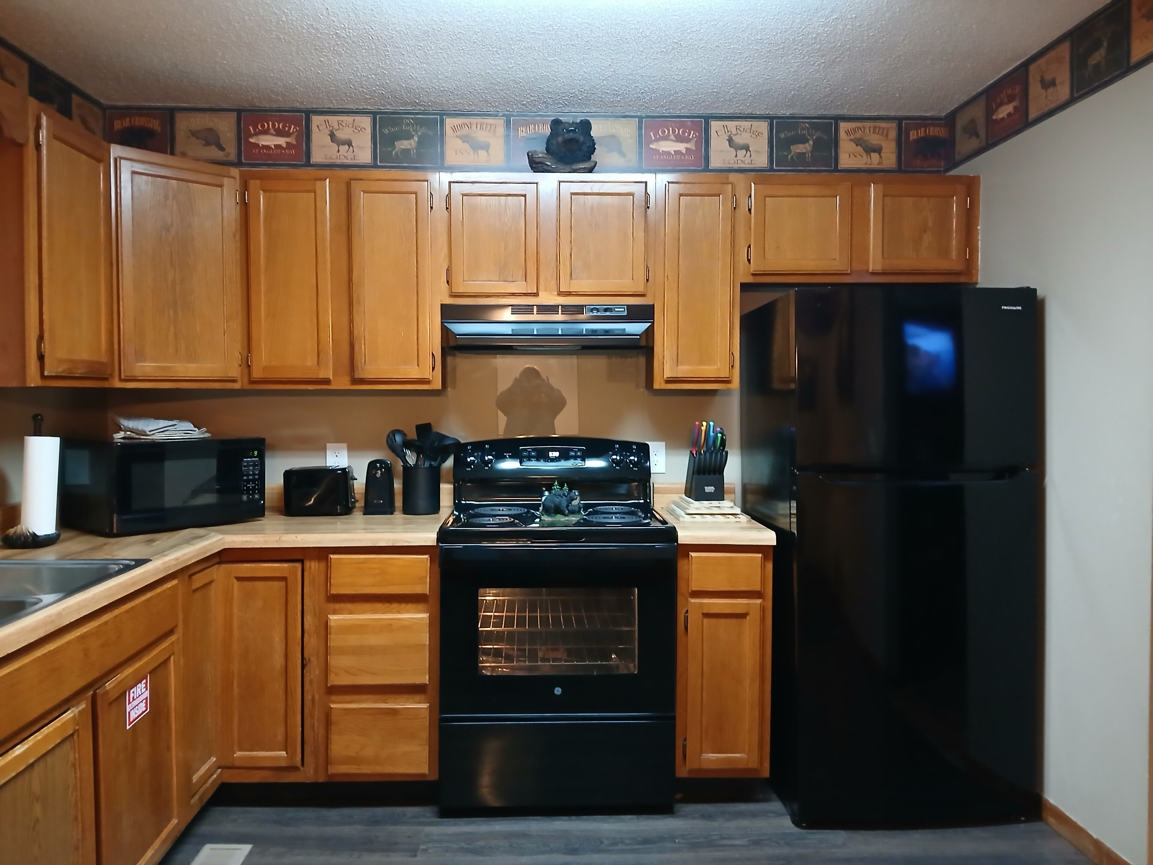 A kitchen with wooden cabinets, a microwave, a stove, and a refrigerator.