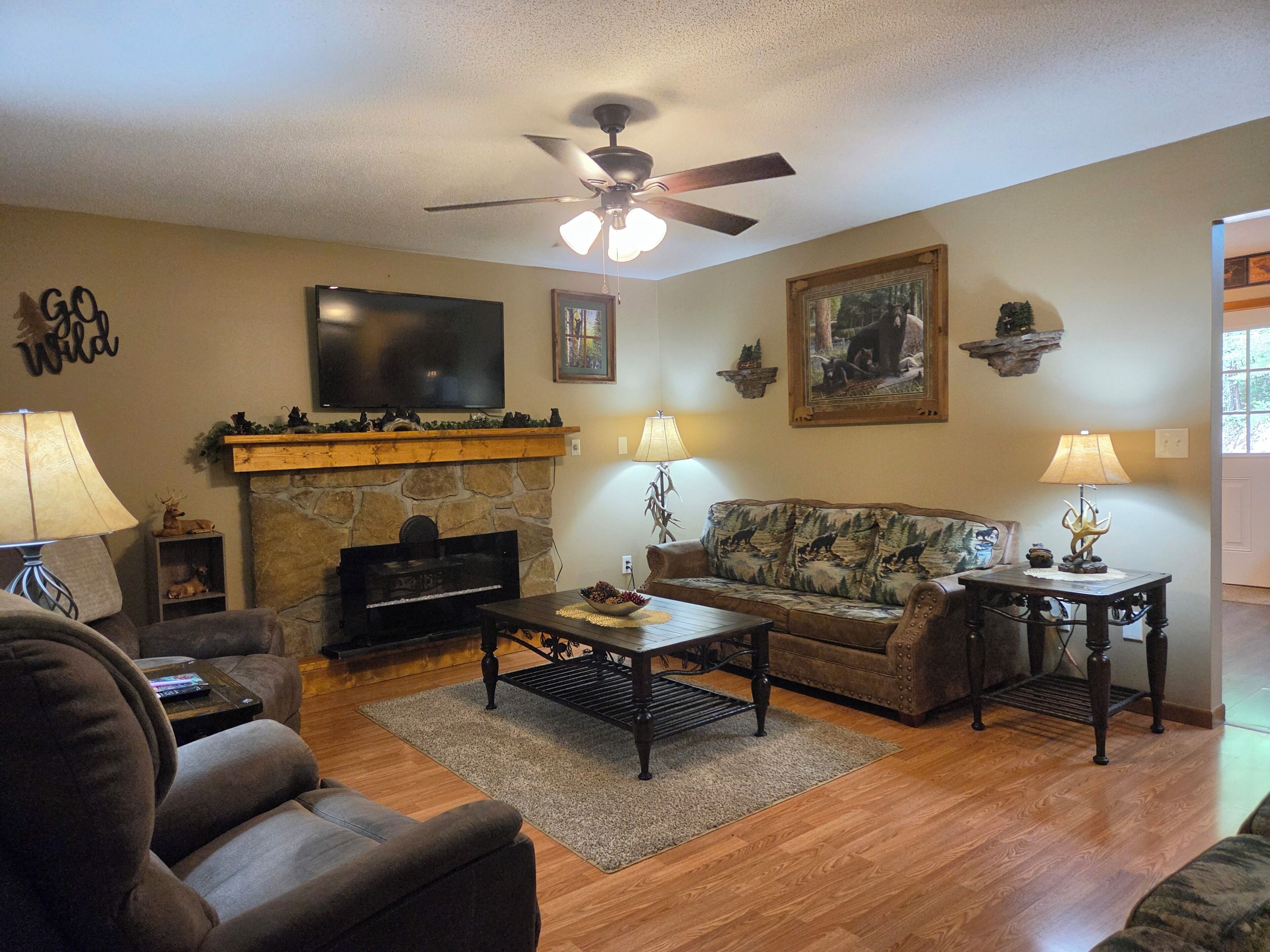 A living room with a fireplace, a television, a ceiling fan, and a couch.