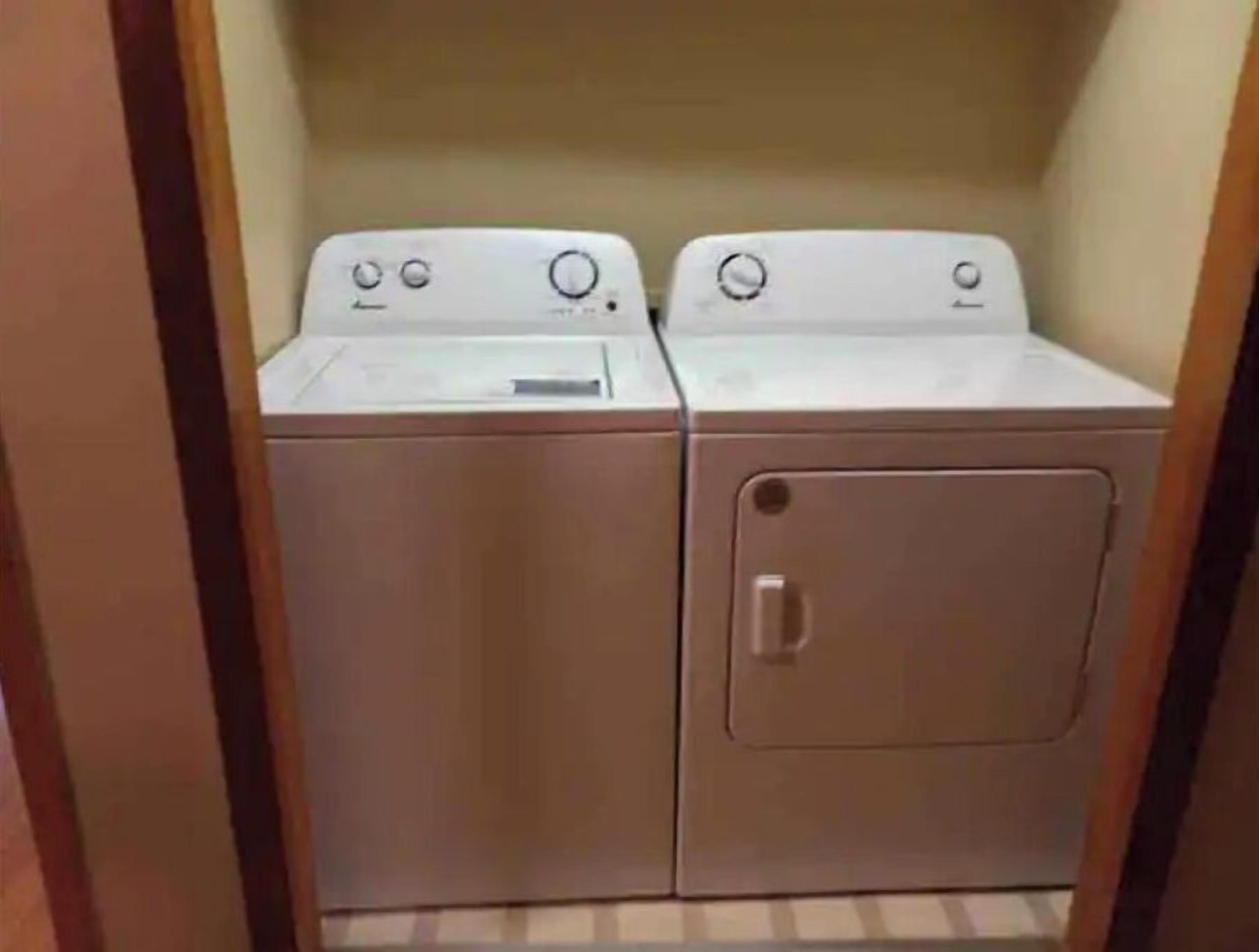 A laundry room with two washing machines and a dryer.