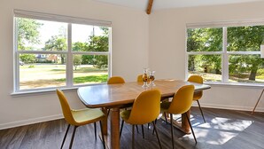 A dining area with a wooden table and yellow chairs, large windows with a view of a green landscape. - Spacious 4BR/3BA with bunkhouse; perfect for family and friends! (Bryan)