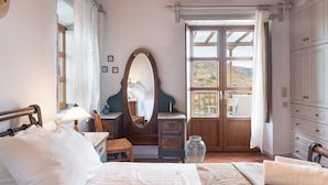 A bedroom with a bed, a dresser, a vanity with a mirror, a window with a view of the outdoors, and a ceiling fan. - Blue Vista Patmos Villa Margarita without the studios (Patmos)