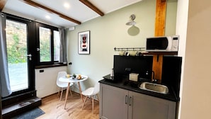 A compact kitchen with a dining area, a microwave, and a coffee machine. - 1 Bedroom Apartment in Pozzuoli (Pozzuoli)