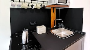 A compact kitchenette with a microwave, a coffee maker, a sink, and a utensil holder. - 1 Bedroom Apartment in Pozzuoli (Pozzuoli)