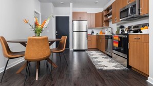 A modern kitchen with wooden cabinets, stainless steel appliances, and a dining area with a table and chairs.