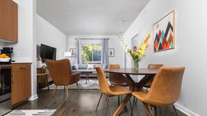 A modern kitchen with a dining area, a sofa, and a TV.