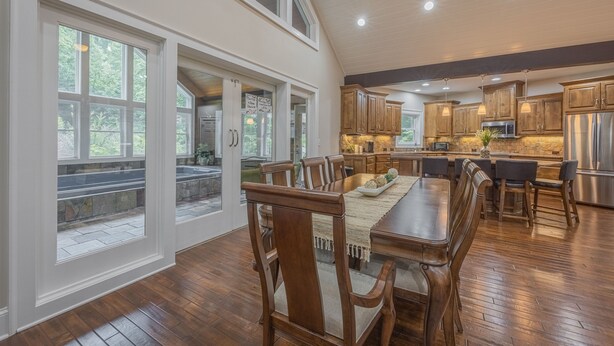 A spacious kitchen with wooden cabinets, a dining area with a large table and chairs, and large windows providing natural light.