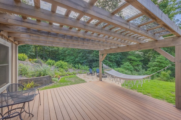 Une terrasse en bois agrémentée d’une pergola, de sièges d’extérieur et d’un hamac.