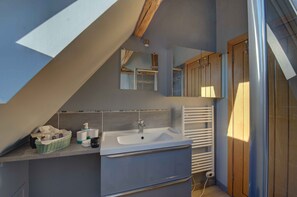A bathroom with a built-in sink, a mirror, a towel rack, and a radiator.