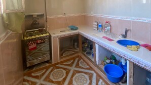 A compact kitchen with a gas stove, a sink, and a patterned floor.