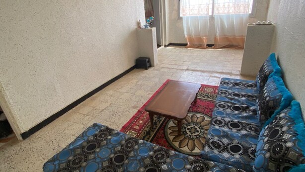 A living room with a patterned sofa, a small wooden table, and a red rug.