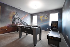 A room with a foosball table and a foosball machine, with Star Wars-themed wall art. - New 12 BD W/heated pool home-12 min to Disney 2480 (Kissimmee)