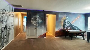 A room with Star Wars-themed decor, including a mural of Darth Vader and a Millennium Falcon. - New 12 BD W/heated pool home-12 min to Disney 2480 (Kissimmee)