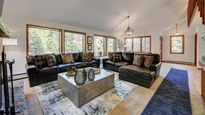 A spacious living room with large windows, a fireplace, and a modern chandelier. -     Private Luxury Retreat in Evergreen, Hot Tub + Multiple Decks (Evergreen)