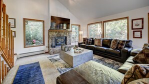 A spacious living room with a fireplace, large windows, a sofa, and a coffee table. -     Private Luxury Retreat in Evergreen, Hot Tub + Multiple Decks (Evergreen)