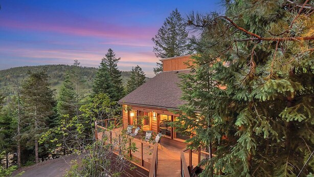 A wooden cabin with a deck, surrounded by trees, and a view of the forested hills. -     Private Luxury Retreat in Evergreen, Hot Tub + Multiple Decks (Evergreen)