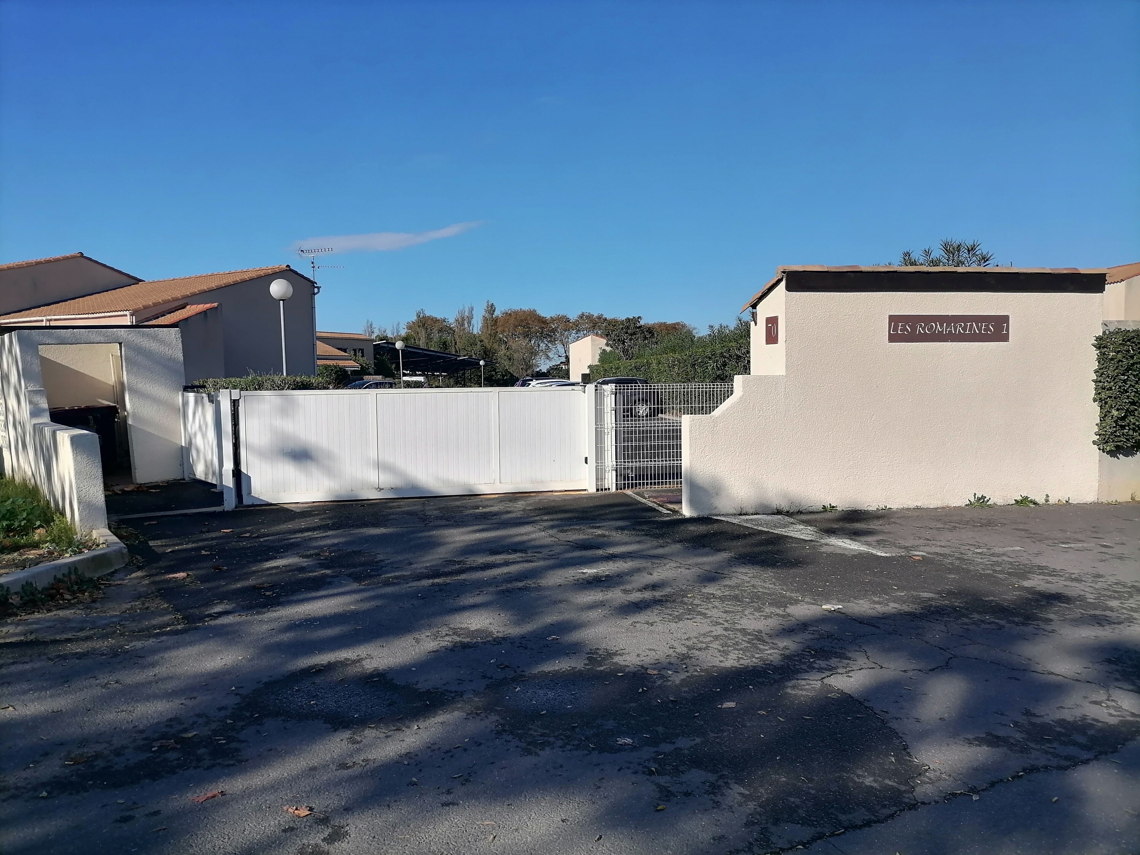 Una entrada con portón a un edificio con un letrero que dice 'LES ROMARINES 1'.